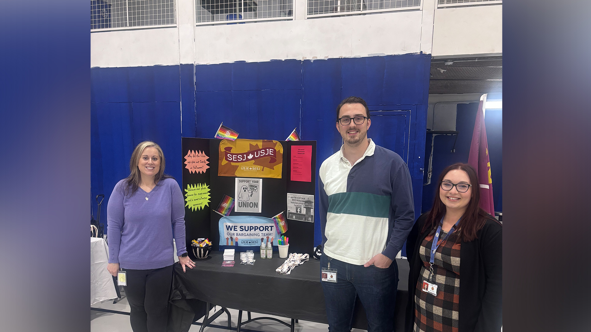 Two women and one man standing in front of USJE booth at wellness fair.